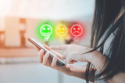 Customer service experience and business satisfaction survey. Close-up image of female hands using mobile smartphone choose face smile